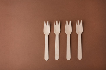 four eco friendly forks on a brown background top view eco friendly tableware wooden forks, disposable tableware