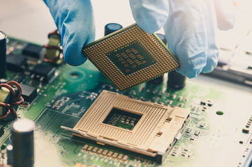 The technician is laying a CPU on the socket of the computer motherboard. the concept of computer,...