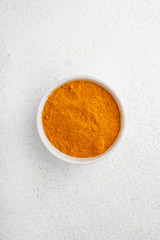 turmeric powder in a white cup on a white table top view