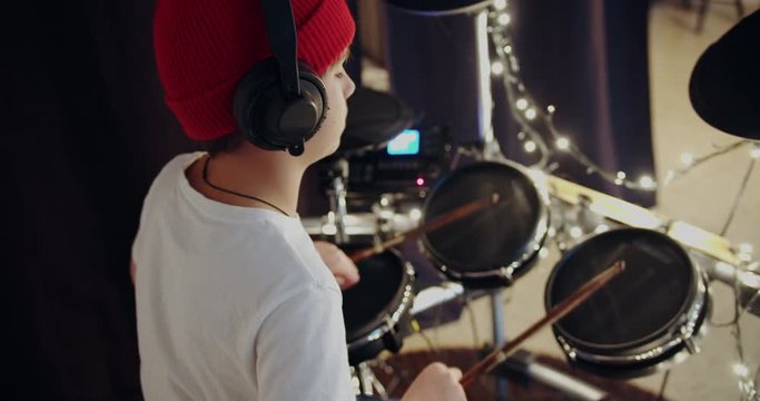 Young teenger boy learning play electronic drums music at living room. Self education at home during covid19 quarantine.