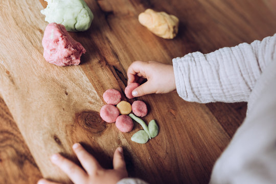 Kinderh&auml;nde kneten bunte Blume auf Holztisch