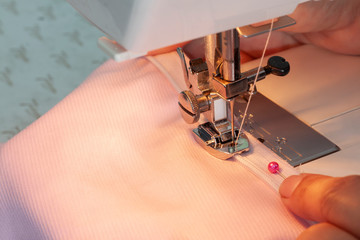 Hand of dressmaker is sewing a invisible zipper with a sewing machine, technology that helps sewing cloth faster and easier. © Pannarai