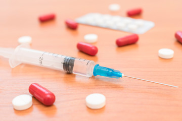 A vaccine in a syringe and tablets with capsules on a medical table during the treatment of a pandemic