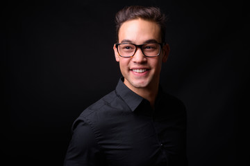 Young handsome multi ethnic businessman against black background