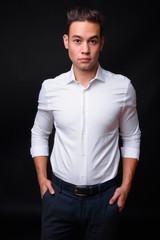 Fototapeta premium Young handsome multi ethnic businessman against black background