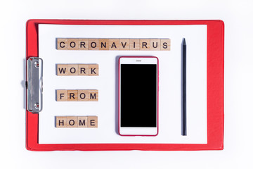 Text from wooden letters coronavirus work from home. Office supplies, red tablet, phone, pencil on the desktop. Flatley layout on a white background. Minimalistic office concept.
