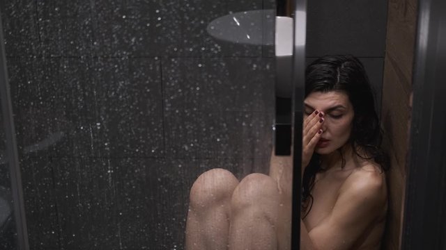 girl is sitting in shower under warm water,woman is sad and crying in shower room at home without clothes,Concept of sadness woman,close up