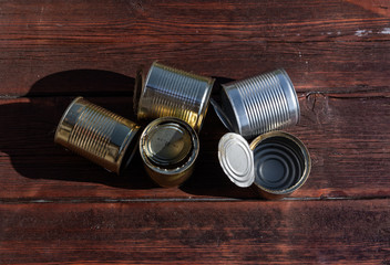 old empty cans on a wooden table, brown wooden background