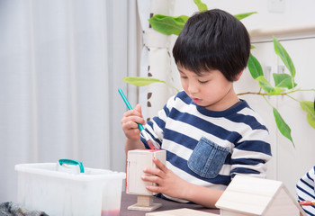 絵の具で作品に色を塗る小学生