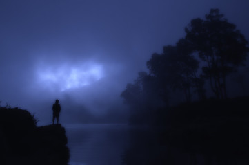 Naklejka premium silhouette of a man standing on lake mountain