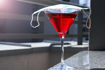 Medical mask on a cocktail glass. Prevention of coronavirus COVID-19. Antiviral protective agents during the world coronavirus pandemic. Working at home during quarantine.