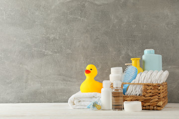 Baby hygiene accessories on wooden table against gray background