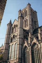 GHENT, BELGIUM - August, 2019: Facade of Saint Nicholas' Church (Sint-Niklaaskerk) with the clock tower of Belfry of Ghent (Het Belfort) at the background, in Ghent. Before before corona crisis