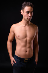 Naklejka premium Young handsome multi ethnic man shirtless against black background