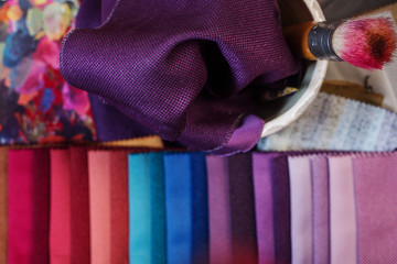 colorfull textile lies on a colorfull palette of the artist.Colored brushes and fabrics.