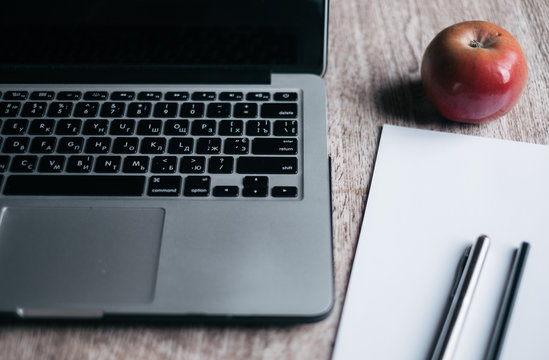 laptop with apple and papers with pens on the table