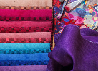 colorfull textile lies on a colorfull palette of the artist.Colored brushes and fabrics.