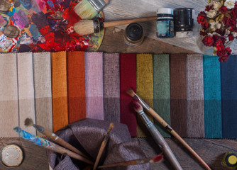 colorfull textile lies on a colorfull palette of the artist.Colored brushes and fabrics.
