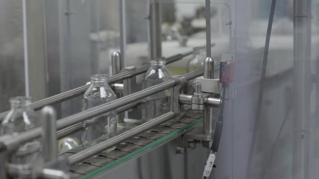 glass bottles on medical solution conveyor line close up medical industry