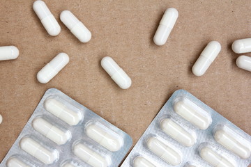 Drugs - white pills in a blister pack on cardboard background - Medicines addiction