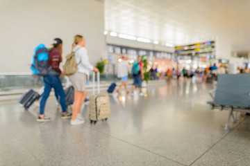Defocused terminal departure check in at airport with walking travelers