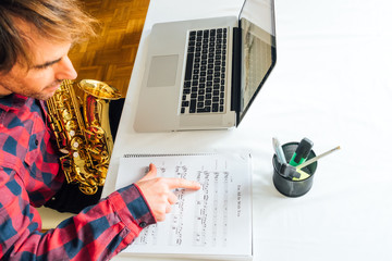 man pointing over notes on sheet music during his saxophone online course
