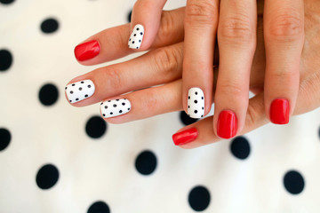 Female hands with a beautiful manicure, on polka dots background.