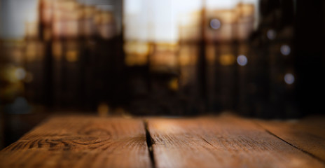 Empty wooden table top on blur light golden bokeh of cafe restaurant, bar in a dark background.