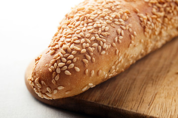 Baguette with sesame seeds on wooden board