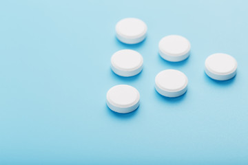 White medicinal tablets in the shape of a pyramid on a blue background.