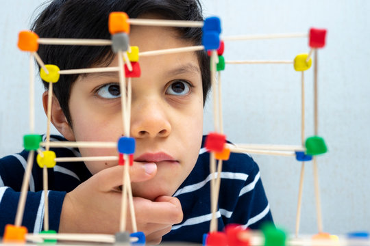 Close up Concentrated boy making a structure with toothpicks and colored plasticine 
