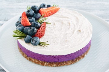 Blueberry cake with strawberry and rosemary. Dessert with cream and berries on a gray wooden background