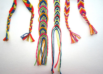 Braided macrame friendship bracelets with tassels on a white background