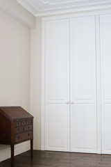 White cabinet doors with brown floor handles and a brown chest of drawers