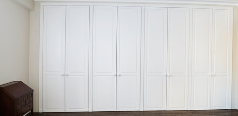 White cabinet doors with brown floor handles and a brown chest of drawers