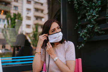 Fototapeta premium A beautiful young caucasian woman puts on a mask. COVID - 19 protection