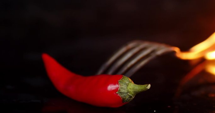 Forkg with red chilli burning in fire flames.