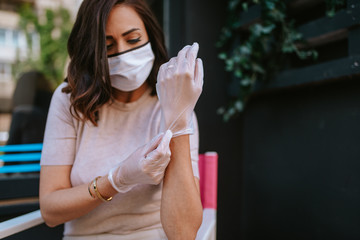 A beautiful young caucasian woman with gloves and a mask in a cafe. COVID - 19 protection
