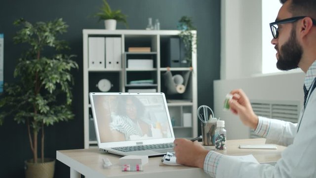 Medic young man in uniform is talking to Afro-American girl online consulting sick woman discussing medication. People and telemedicine concept.