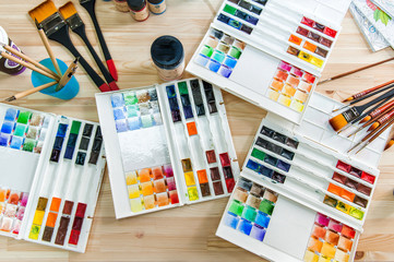 Watercolor paints, art brushes, pens accessories for the artist long, flat lie on top top View