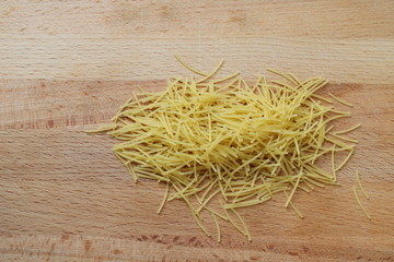 a handful of thin pasta on a wooden Board