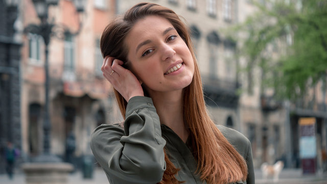 Close up portrait of a beautiful smiling girl with brown hair. Urban city background