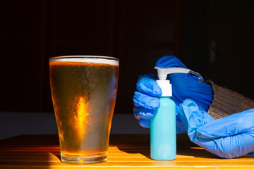 Person with gloves and disinfectant having a beer in a restaurant. COVID-19.