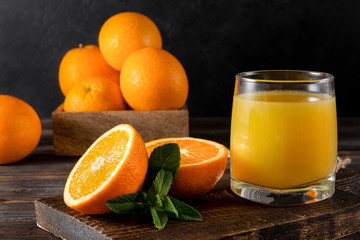 orange juice with mint , fresh whole and sliced oranges on a black , refreshing drink