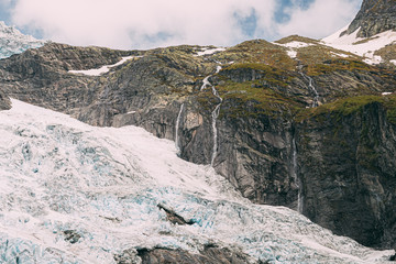 Jostedalsbreen National Park, Norway. Close Up View Of Melting Ice And Snow, Small Waterfall On Boyabreen Glacier In Spring Sunny Day. Famous Norwegian Landmark And Popular Destination. Close Up