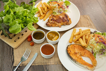 Salmon fish and Chicken grilled steak dishes with barbecue, mushroom and black pepper sauce. Wooden table.