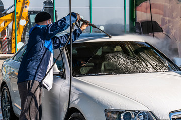 Young man washing his car in a self-service car wash station