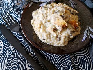 Tasty risotto with chicken, fresh herbs vegetables on a white plate