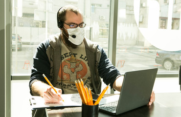 An online lesson during quarantine. Young teacher in medical mask conduct an online lesson.