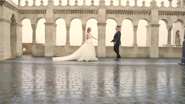 young couple walking silhouette go together past architecture of old castle and city. on the background of columns of balusters arches, letters, vintage. Historic place. luxury fashion, bride, groom